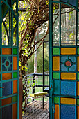 Blick durch bunte Glastüren auf schmiedeeiserne Gartenmöbel