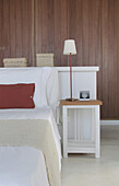 White painted bed with freestanding headboard and wooden fitted wardrobes