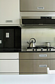 Moderne Küche mit Backofen aus Edelstahl und Wasserkocher auf dem Kochfeld