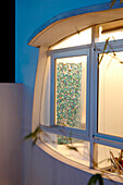 Bathroom viewed through window of stucco finished exterior with white aluminium frame