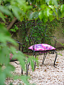 Wrought iron chair with pink floral pattern on gravel patio