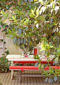 Bench seats with red cushions in walled garden patio