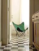 Green folding chair on chequered floor viewed through doorway