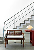 A wood stool and side-table with red patina and a modern table lamp