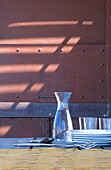 Glassware and crockery on table of steel studded veranda