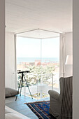 Telescope in living room with atrium and view to sea
