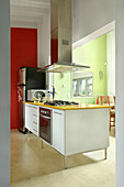 Küche mit roter Wand und Dunstabzugshaube über dem Kochfeld in gelber Formica-Arbeitsplatte
