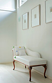 White upholstered chaise longue below artwork and window