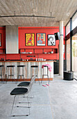 Recycled kitchen counter with Lapacho top and cast iron stools with black leather seats plastered walls painted red