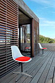 Treated pinewood deck with Jacobsen chairs with red seats and Lapacho wood screen