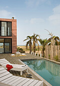 House exterior with sunloungers on poolside decking