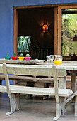 Oak table and bench seats with cactus at doorway to blue painted veranda