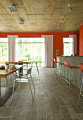 Red open plan kitchen with flagstone floor and large curtained windows