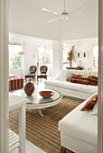 Ganz in Weiß gehaltenes Wohnzimmer mit Terrakotta- und grünen Details und einem L-förmigen Sofa