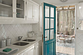 Kitchen with painted turquoise door and view to outdoor terrace with pinewood fence