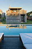Concrete and stone building exterior on narrow plot reflected in water surface of pool