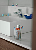 Toothbrushes and toothpaste beside ceramic wash basin
