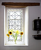 Vase mit Sonnenblumen auf sonnenbeschienener Fensterbank mit Originalbalken