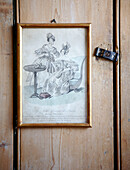 Black and white framed sketch hangs on wooden door with latch