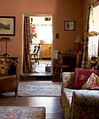 Patterned rugs on wooden floor of living room with view through curtained doorway to kitchen