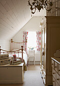 White painted bedroom with floral curtains and brass bed