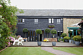 Plastic dog statues in the garden contrast against the clapperboard and brick building exterior 