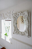 Bathroom window detail with ornate painted white mirror and Wash lettering on the wall