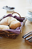 Bread rolls in basket with purple napkin