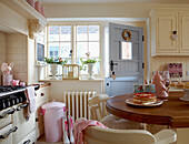 Cream sunlit country kitchen with pink accessories and pastel blue back door