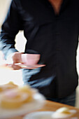 Man in a blue shirt carrying a hot cup of tea