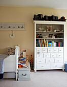 Storage unit with toy trains and books at foot of child's bed