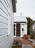 Bemalte Hausfassade mit Topfpflanzen an offener Tür in Wairarapa auf der Nordinsel Neuseelands
