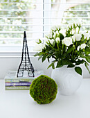 Cut roses and model of the Eiffel Tower on desk top in window