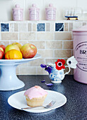 Teekuchen auf der Theke mit Obstschale und rosa Küchenutensilien