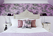 Bedroom detail with patterned wallpaper and matching lamps on bedside cabinets