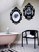 Attic bathroom with metal picture frames and pink freestanding bath