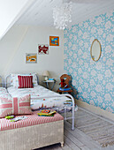 Child's room with floral patterned wallpaper and metal framed twin beds