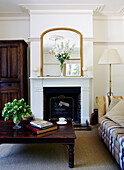 Gilt framed mirror on fireplace with wooden coffee table in townhouse living room