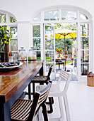 Hölzerne Frühstücksbar mit Hocker und Blick durch Gartentüren