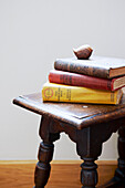 Hard backed books on wooden stool