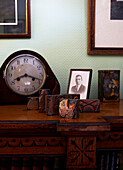 Group of objects including a mantle clock and photos on a wooden desk