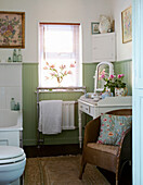 Badezimmer mit Vintage-Tisch und Spiegel und blassgrüner Wandverkleidung