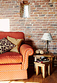 Orangefarbenes Polka-Dot-Sofa mit Beistelltisch vor freiliegender Backsteinwand
