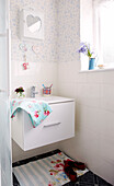 Wall mounted wash stand below heart shaped mirror on bathroom cabinet