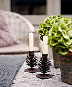 Kerzenständer aus Messing und Topfpflanzen auf einem Korbtisch