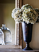 Getrocknete Hortensie in Vase mit spiegelndem Glasgeschirr in einem Landhaus