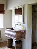 Mirror above marble wash basin with laundry baskets in country home
