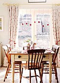 Wooden chairs at table in dining room with Christmas baubles in doorway