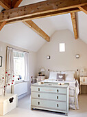 Chest of drawers at food of bed in room with high beamed ceiling