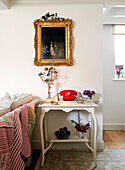 Gilt framed artwork above side table with rotary dial telephone